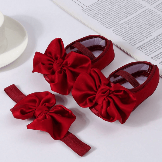 Red baby shoes and headband set on a white background