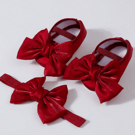 Red baby shoes with large bows on a white background