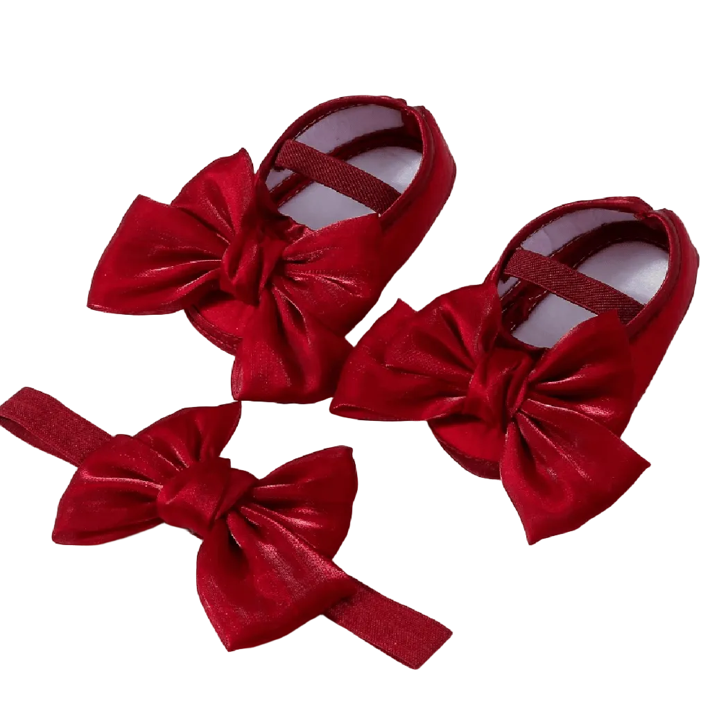 Red baby shoes with large bows on a white background