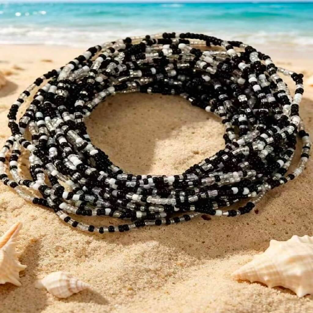 Black and white beaded necklace on sand with ocean background