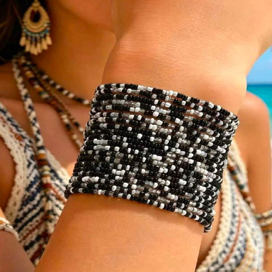 Close-up of a person wearing a black and white beaded bracelet with a blurred background.