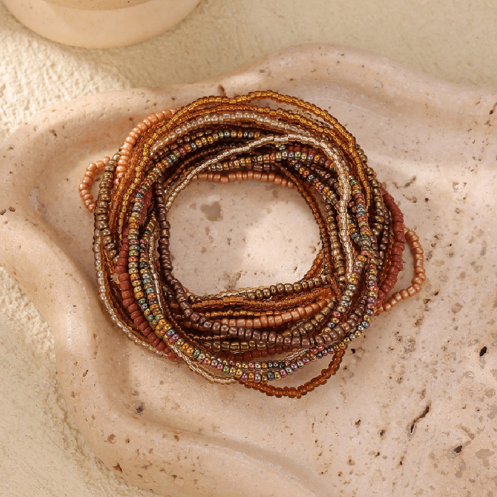 Stack of beaded bracelets on a textured stone surface