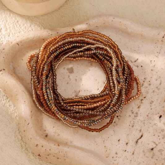 Stack of beaded bracelets on a textured stone surface