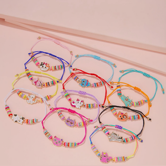Colorful bracelets with cat charms on a pink background