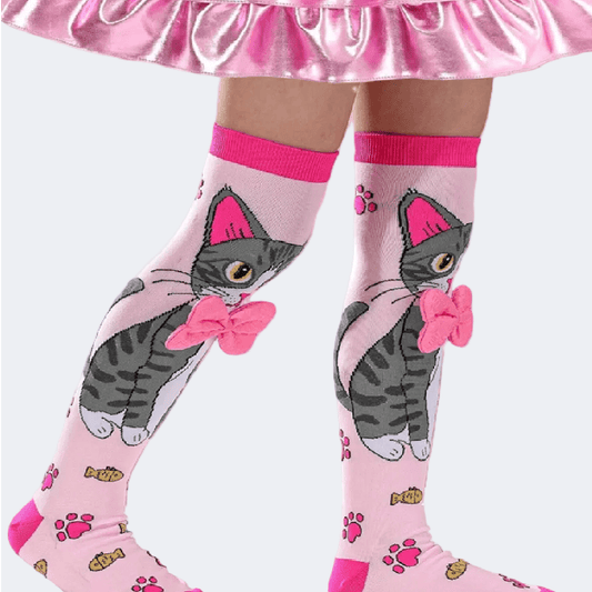 Pink knee-high socks with cat design worn by a person in a pink skirt.
