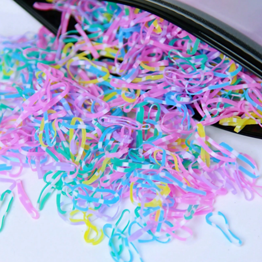 Colorful rubber bands on a white surface with a black tray.