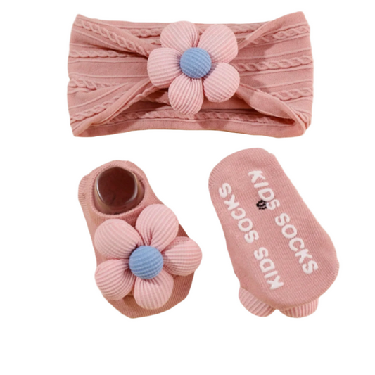 Pink baby headband and socks with flower design on a light peach background