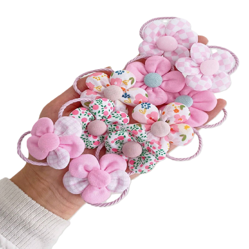 Hand holding pink floral hair ties against a white background