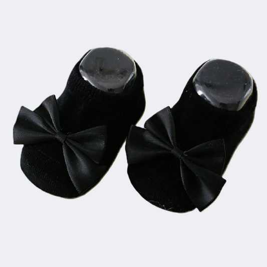 Black baby shoes with bow details on a white background