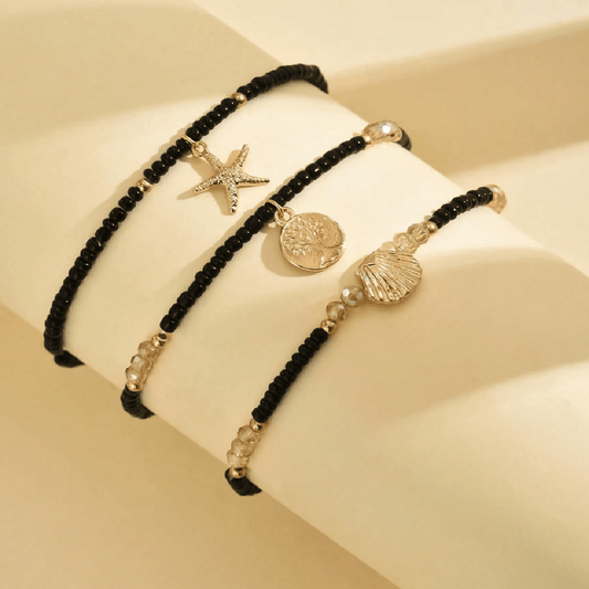 Ankle bracelet with star and shell charms on a sandy background