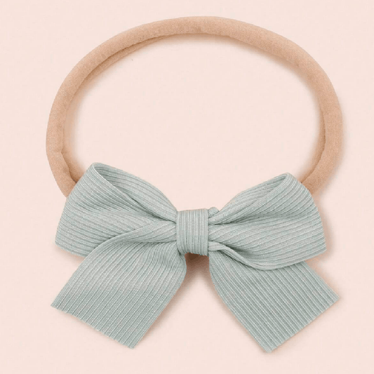 Light blue bow on a beige headband against a light pink background