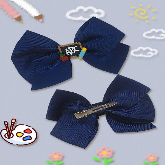 Two navy blue hair bows with decorative clips on a light blue background with doodles.