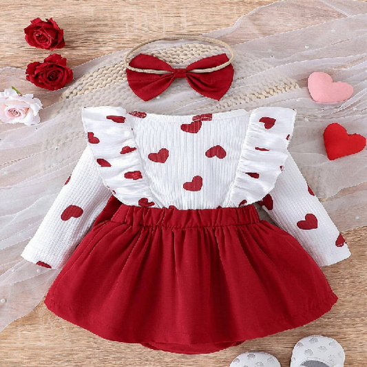 Children's outfit with white top and red skirt, accompanied by a headband and heart-shaped decorations on a wooden surface.