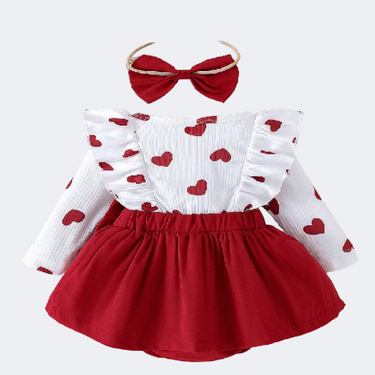 Children's outfit with white top and red skirt, accompanied by a headband and heart-shaped decorations on a wooden surface.