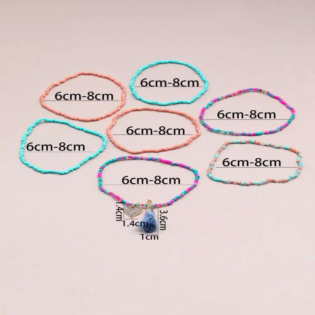 Colorful beaded anklets on a foot with a plain background