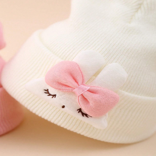 White baby bootie with a pink bow on a beige background