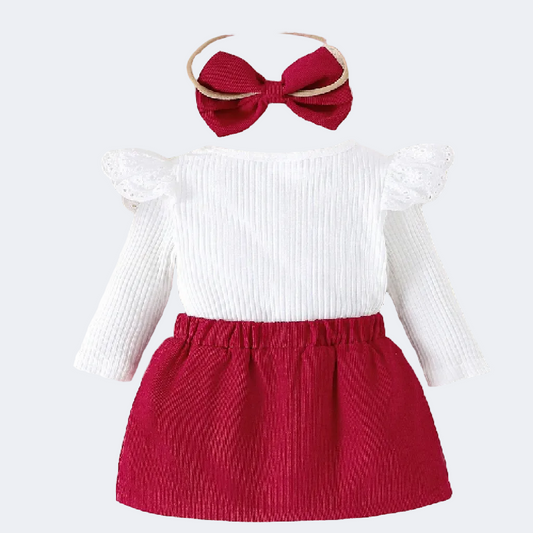 Children's outfit with white top and red skirt on a textured surface