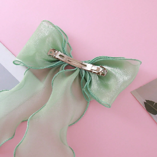Green bow hair clip on a pink background