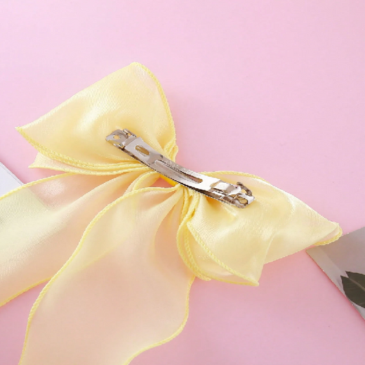 Yellow hair bow with a clip on a pink background