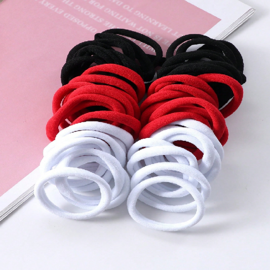 Set of red, black, and white hair ties on a pink background