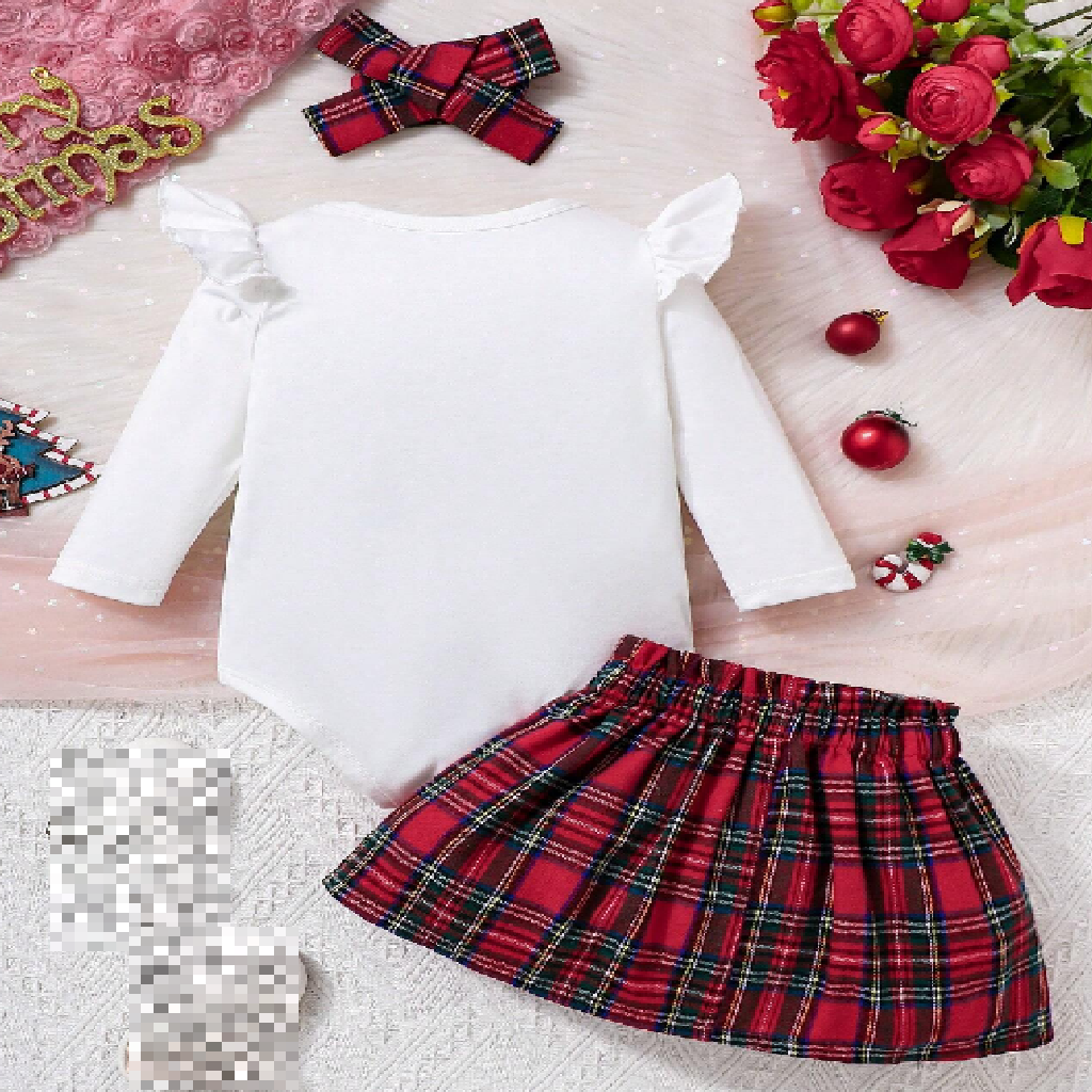 Red plaid skirt with white top on a textured surface with decorative items.
