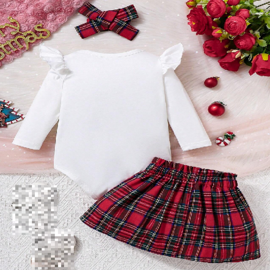 Red plaid skirt with white top on a textured surface with decorative items.
