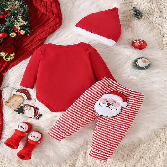 Baby Christmas outfit with red onesie, striped pants, and Santa hat on a fluffy white surface.