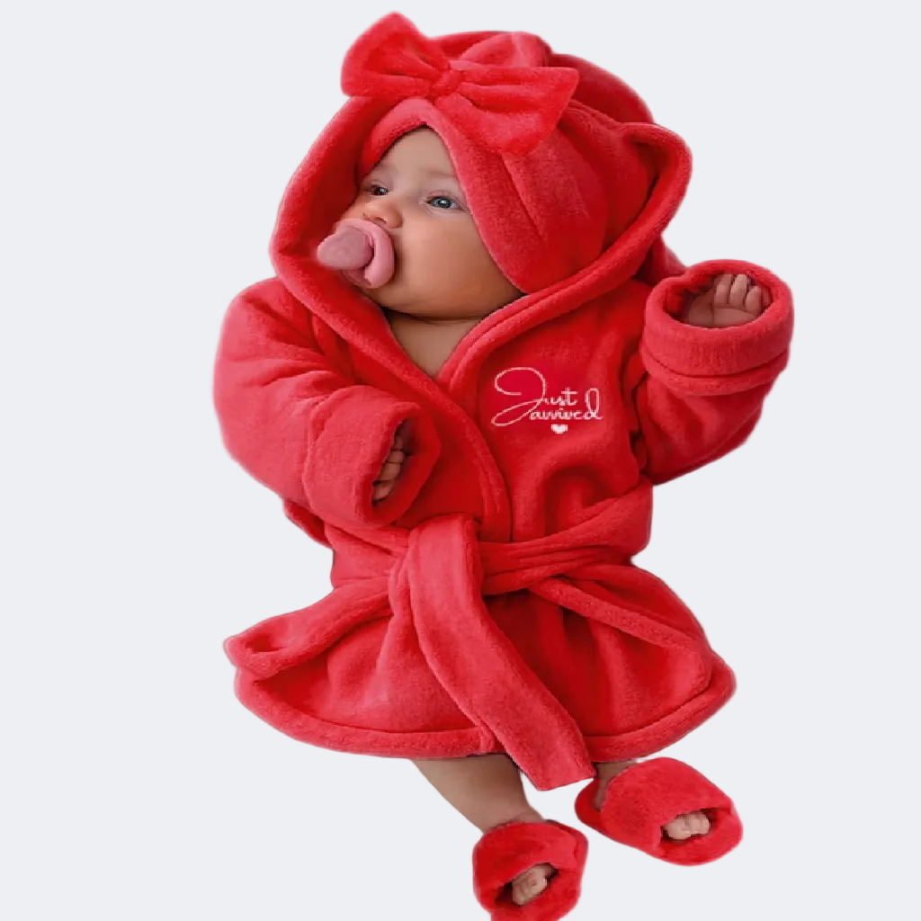 Baby in a red hooded outfit with a bow on a white background