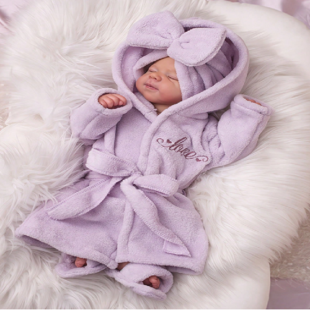 Newborn baby in a purple robe with a bow