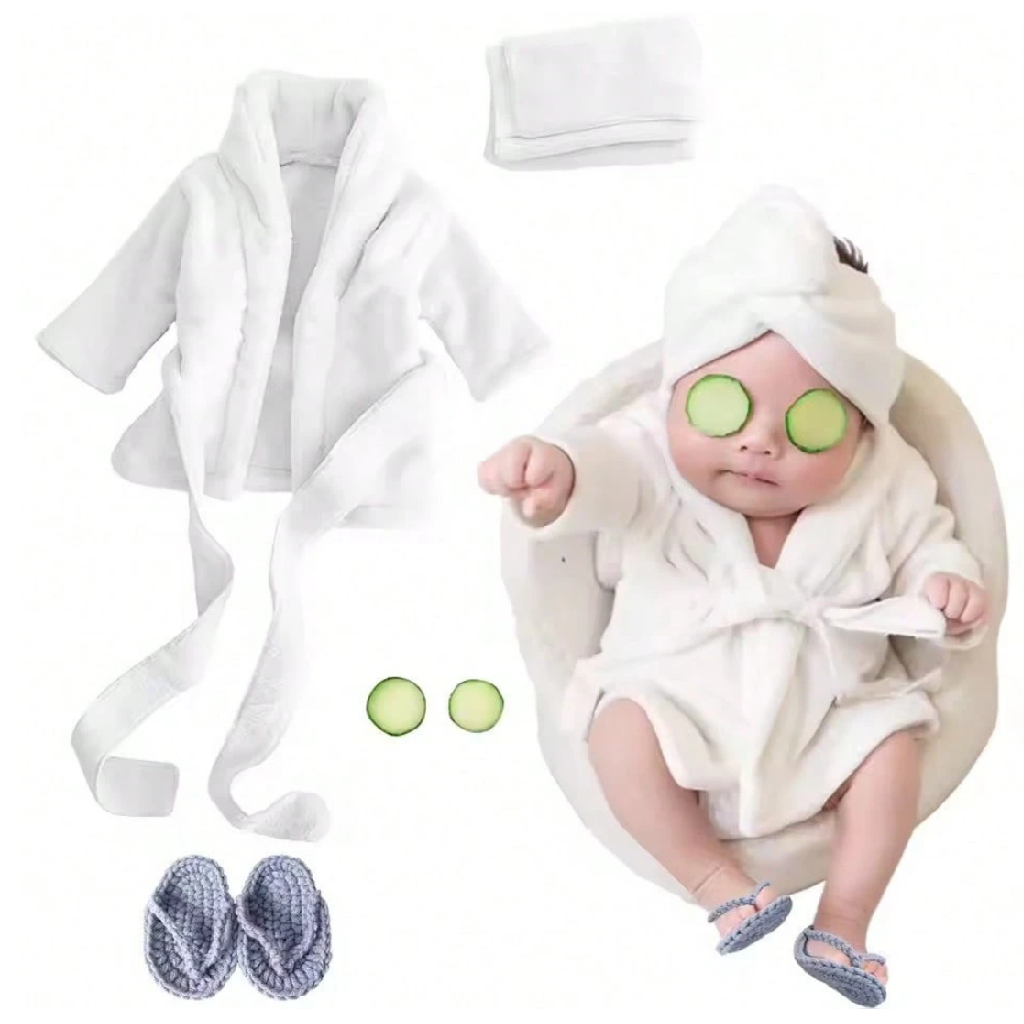 Baby in a white robe with cucumber slices on eyes, surrounded by bath accessories.