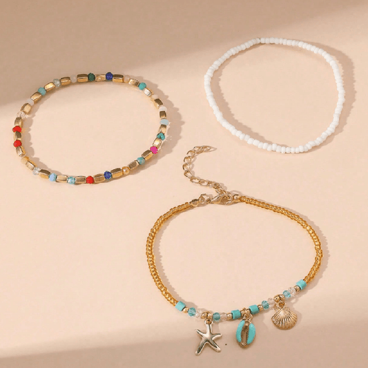 Three necklaces with beads and charms on a beige background