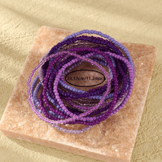Stack of purple beaded bracelets on a stone surface