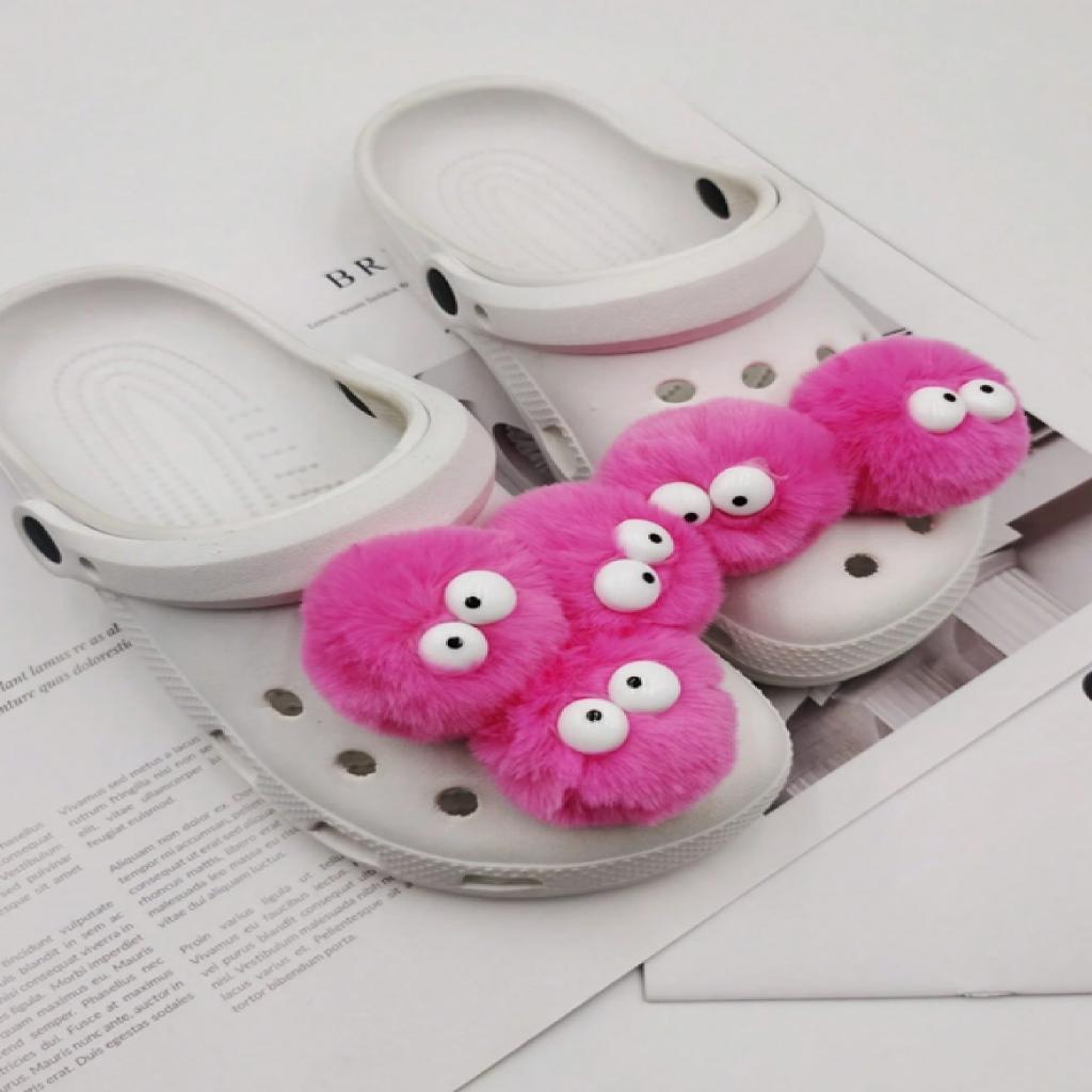 White slippers with pink fuzzy monsters on a white background
