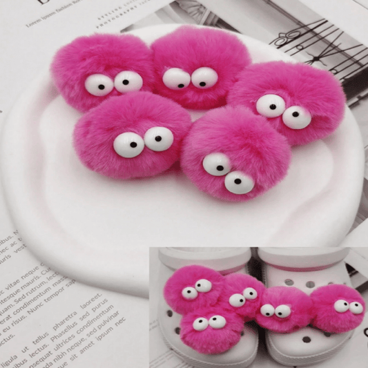 Pink fuzzy slippers with googly eyes on a white surface.