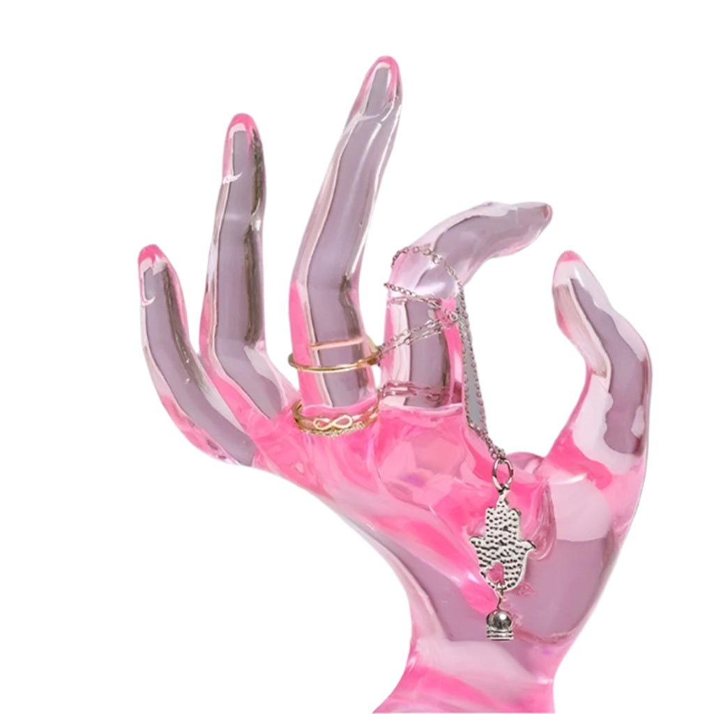 Pink and clear hand-shaped display holding a necklace and rings