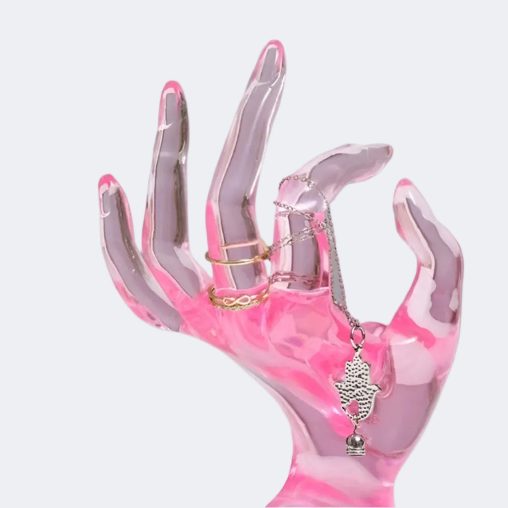 Pink and clear hand-shaped display holding a necklace and rings