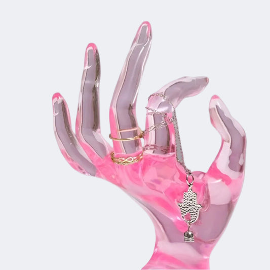 Pink and clear hand-shaped display holding a necklace and rings
