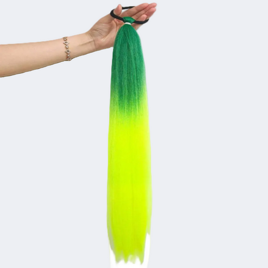 Green to yellow ombre hair extension held by a hand on a white background