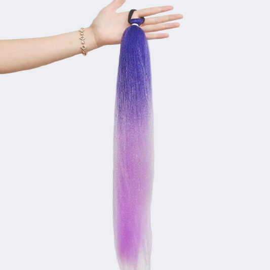Purple hair extension held by a hand on a white background