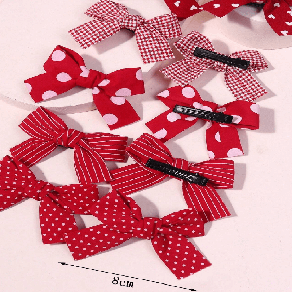 Red and white polka dot hair bows with clips on a light pink background