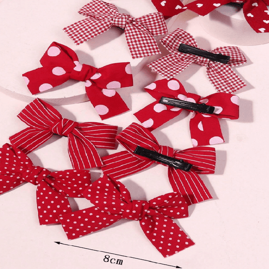 Red and white polka dot hair bows with clips on a light pink background