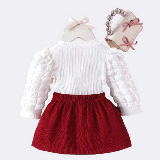 White long-sleeve top with ruffled details and a red skirt on a pink background