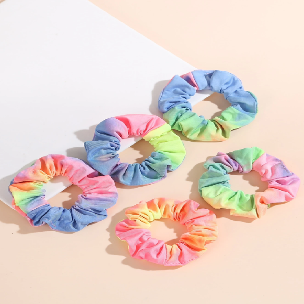 Set of six colorful tie-dye scrunchies on a light background