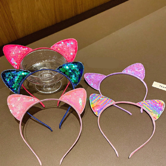 Two colorful cat ear headbands on a brown surface.