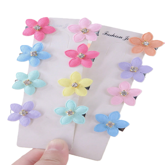 Colorful flower-shaped hair accessories on a card with a hand holding them.