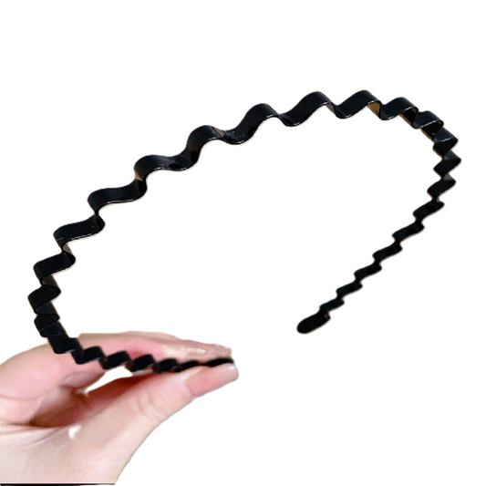 Black hair tie with wavy design held by a hand on a white background