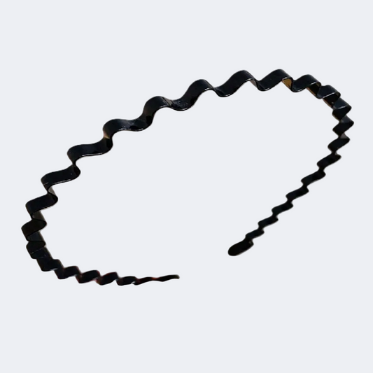Black hair tie with wavy design held by a hand on a white background
