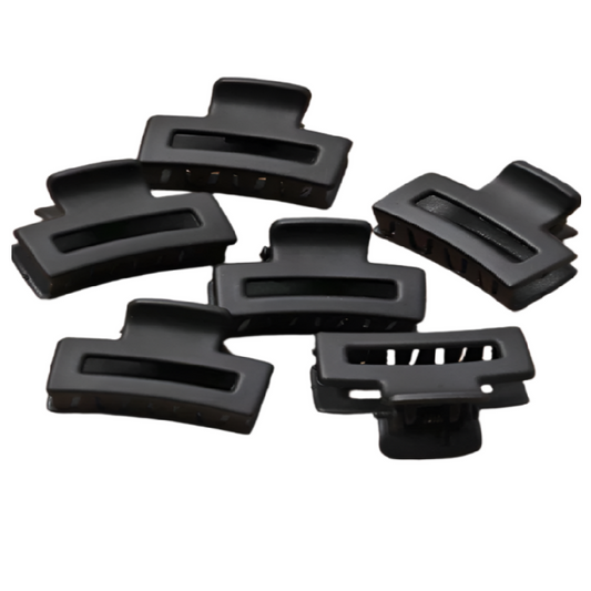 Set of black hair clips on a brown background with a ruler for scale.