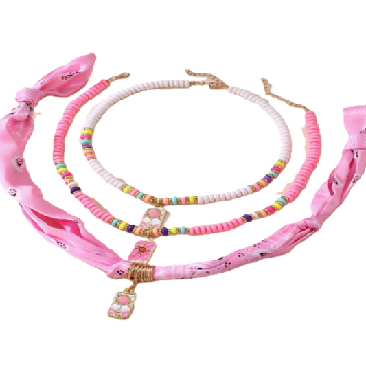 Set of pink accessories including a headband, necklace, and hair tie