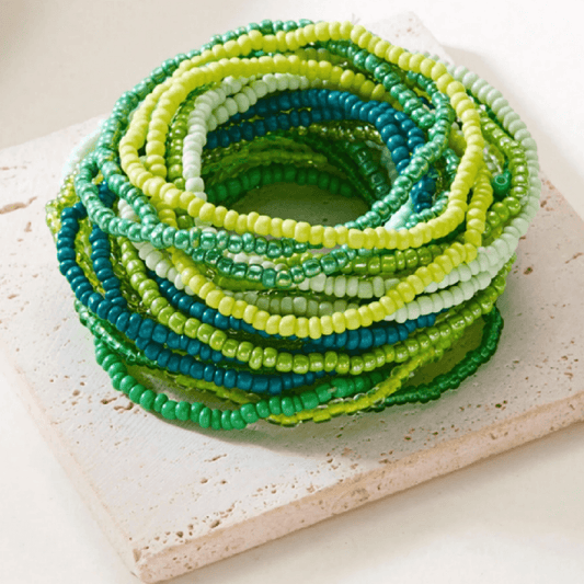 Stack of green and blue beaded bracelets on a textured surface